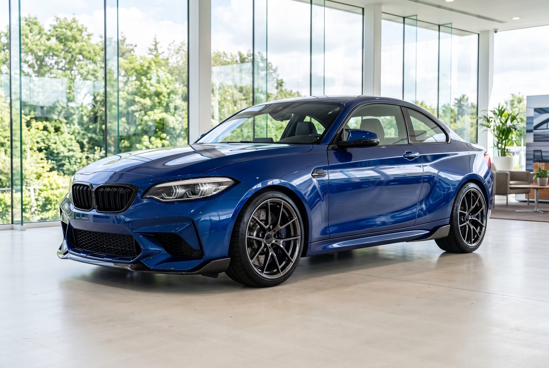 Blaues BMW M2 Competition Coupé von schräg vorne im Ausstellungsraum.