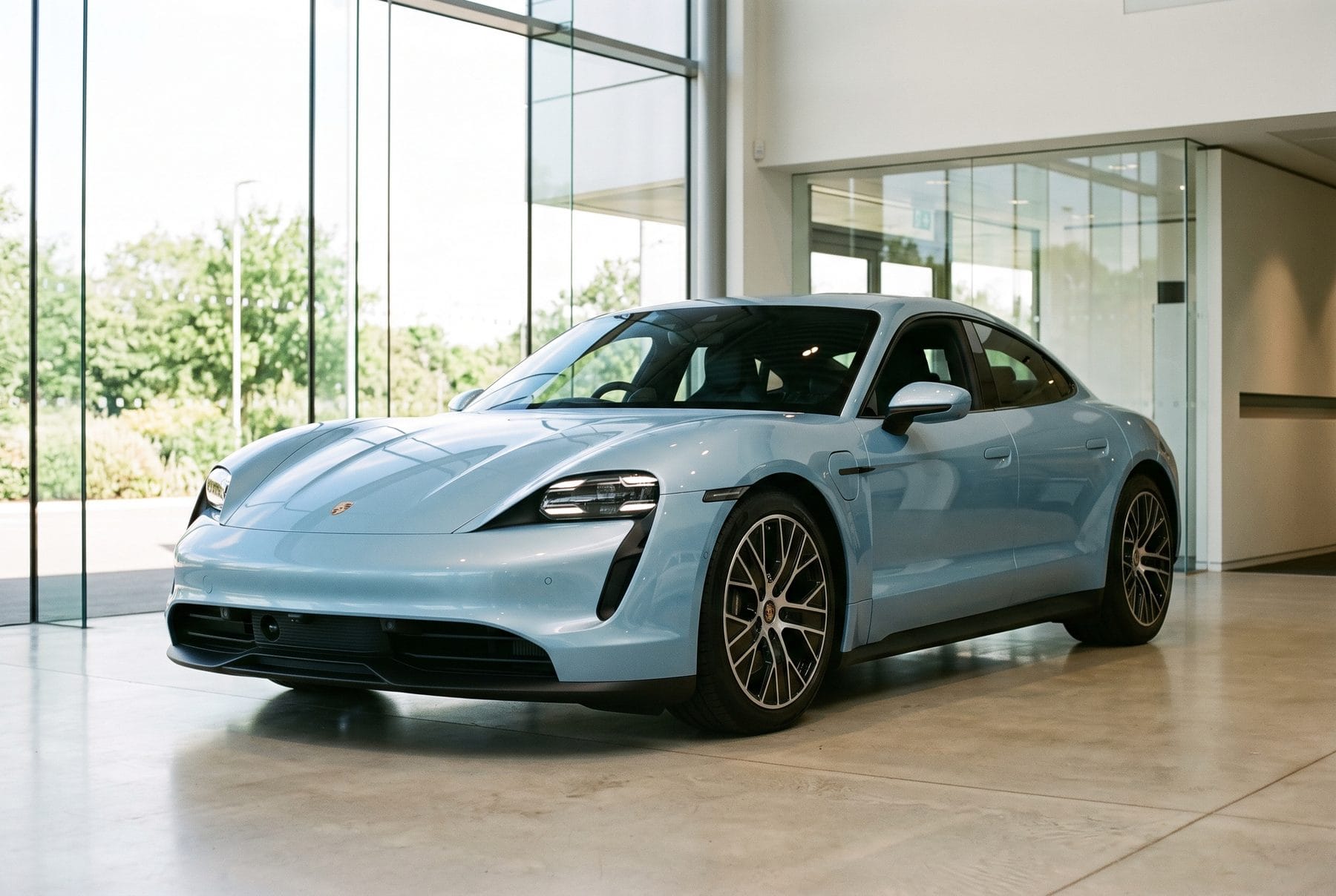 Hellblauer Porsche Taycan 4S von schräg vorne im Ausstellungsraum.