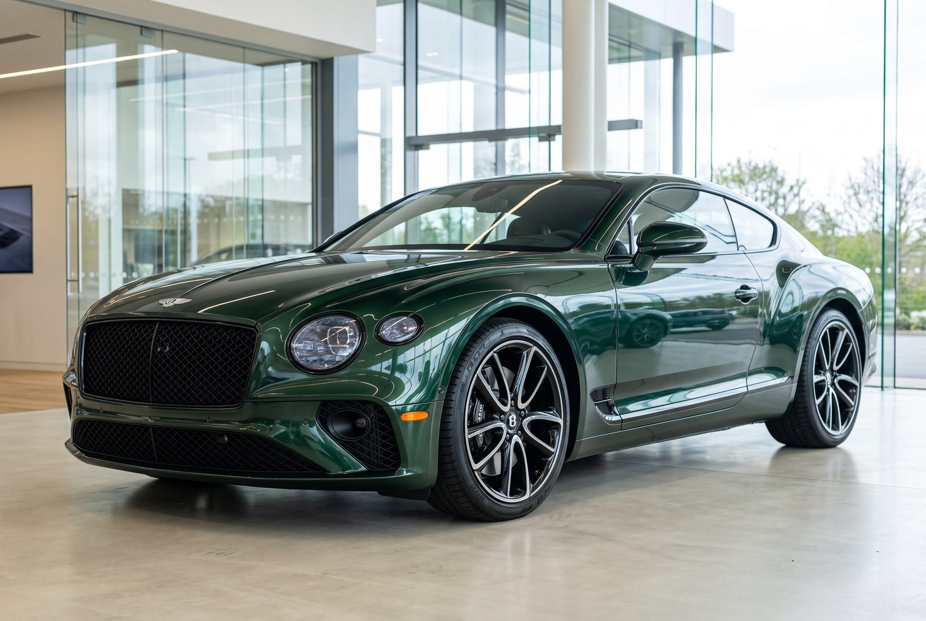 Dunkelgrüner Bentley Continental GT von schräg vorne im Ausstellungsraum.